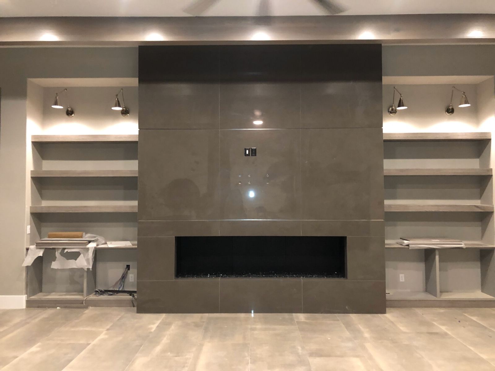 Fireplace wall clad floor to ceiling in large-format gray tile, with a linear fireplace and tile floor