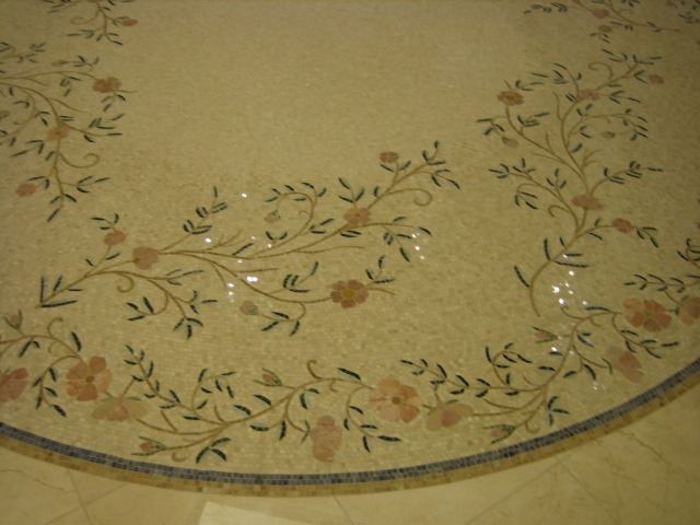Round floor medallion in fine mosaic tile with a pattern of flowering vines and a blue border