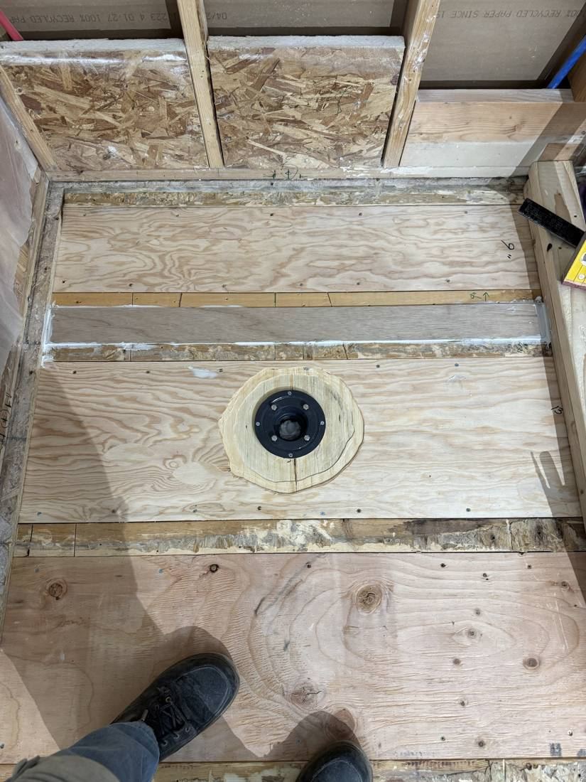 New plywood subfloor with the drain flange set in place