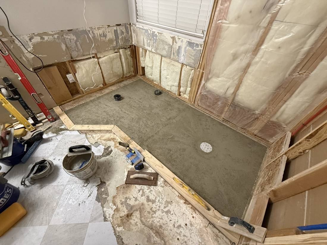 Sloped mortar bed floated to a drain in the bare shower area